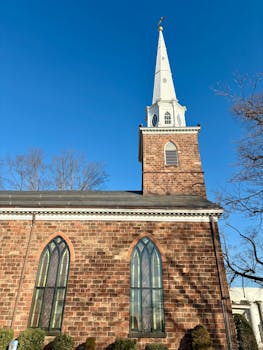 A beautiful historic church with a tall steeple set against a clear blue sky in Dumont, NJ.